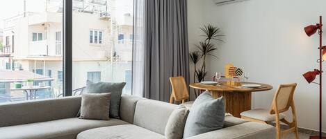 A modern living room with a grey sofa, a round wooden table, and a dining area.