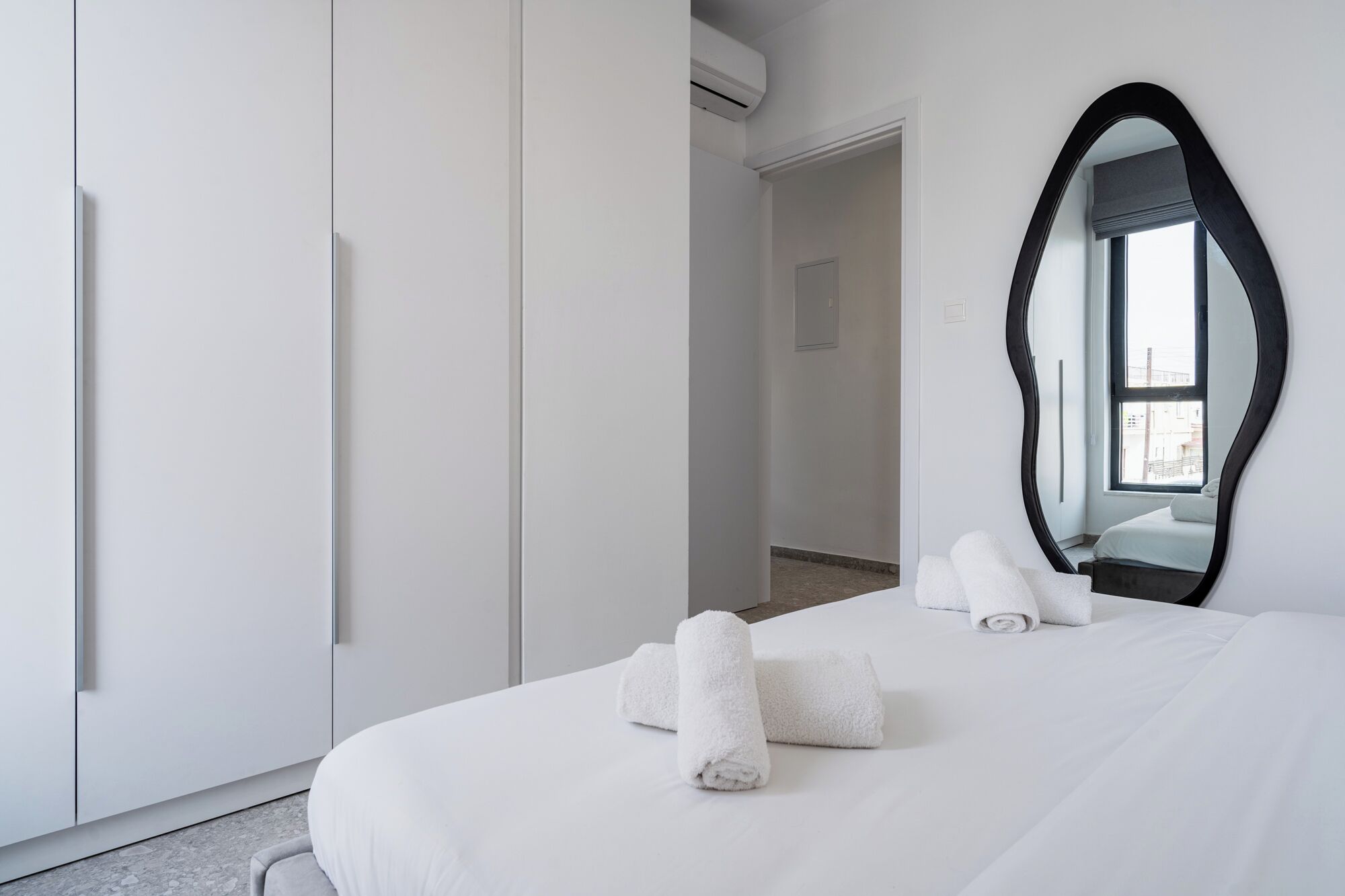 A hotel room with a bed, a large mirror, and a wardrobe.
