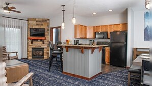 Una cucina moderna con isola centrale, mobili in legno, forno a microonde integrato e frigorifero nero.