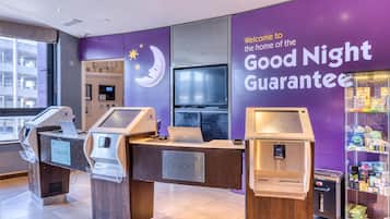 A check-in counter with a 'Check In' sign, a television, and a vending machine with snacks.