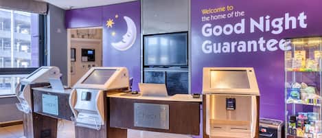 Una reception con una insegna 'Check In', una televisione e una macchina distributrice di snack.