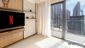 Ein modernes Wohnzimmer mit Flachbildfernseher, Holzbögen und einem großen Fenster mit Blick auf die Stadt.