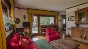 Un salon avec un canapé rouge, une table basse en bois, un téléviseur et un meuble.
