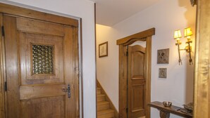 Une porte en bois avec un panneau de verre, un escalier et des luminaires fixés au mur.