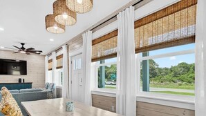 A modern living room with a large window, a dining table, and a sofa. - Coastal Retreat (Rockport)