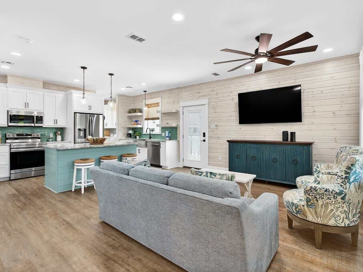 Una cocina moderna con armarios blancos, una isla central y una zona de comedor con sofá y sillones.
