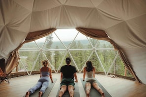 Una carpa con un diseño de ventana geométrico, una colchoneta de yoga y una silla.