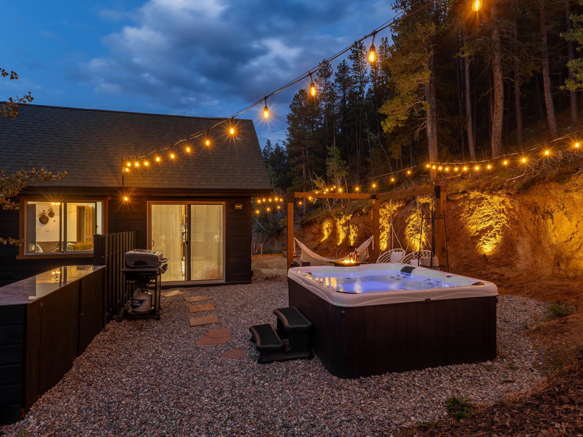 A cozy outdoor area with a hot tub, string lights, and a wooden deck.