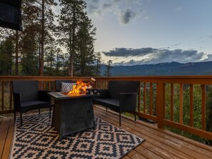 A deck with a fire feature, two chairs, and a patterned rug. - Geo Dome Group Retreat | 3 King Beds & Game Room (Bailey)