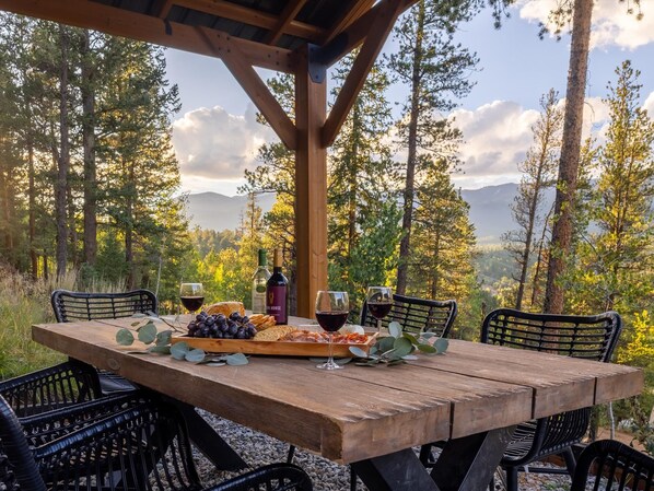 A wooden table set outdoors with a view of a forest and mountains. - Geo Dome Group Retreat | 3 King Beds & Game Room (Bailey)