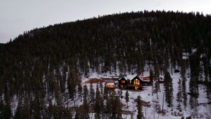 A cabin in a forested area with snow on the ground.