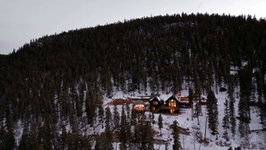 A cabin in a forested area with snow on the ground.
