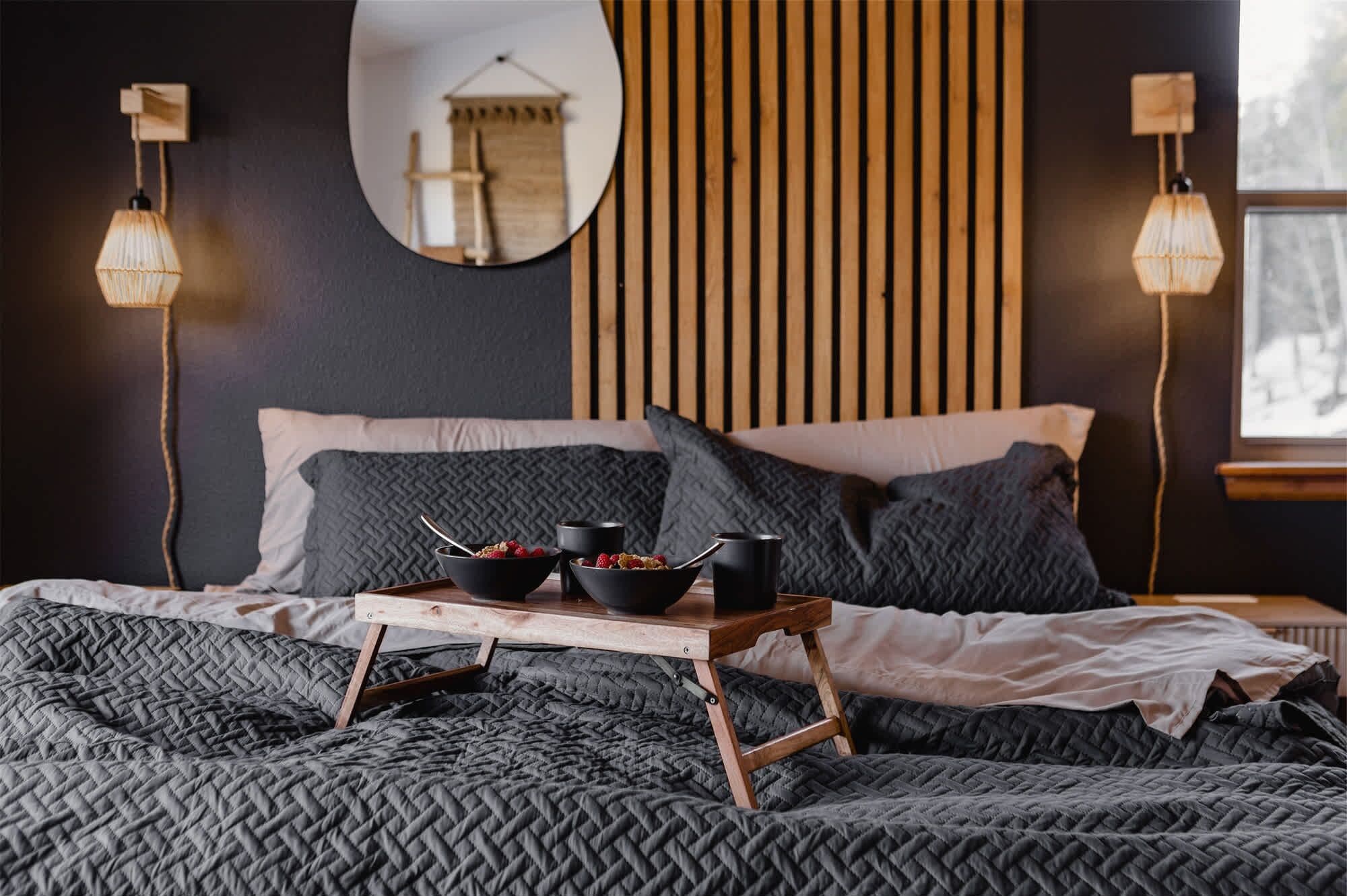 Ein Schlafzimmer mit Bett, Nachttischen, einem Spiegel und einem Fenster.