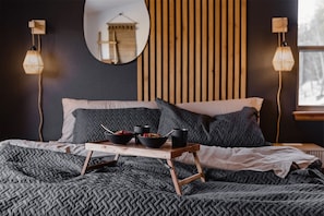 Een slaapkamer met een bed, nachtkastjes, een spiegel en een raam.