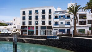 Un bâtiment situé sur la côte, doté de plusieurs étages, de balcons et d’un mur de pierre en premier plan.