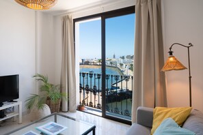 A modern living room with a large sliding glass door to a balcony, a television, a coffee table, and a lamp. - LIVING EL CHARCO-Perfect Views & Location (Arrecife)