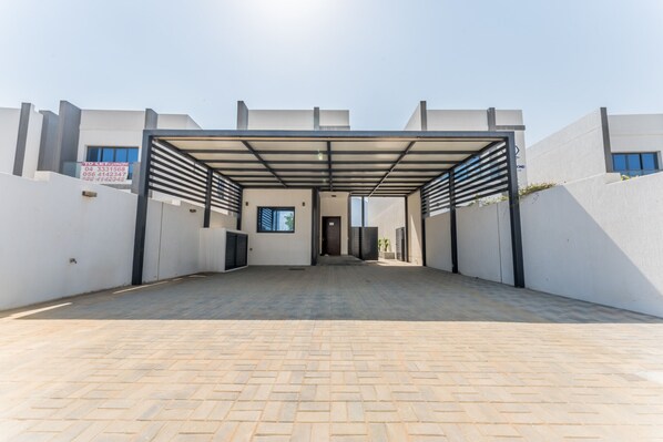 A modern building entrance with a covered walkway and a clear sky. - Sea Views 4BR + Assistant's Room Villa with Private Pool, Sharm - Al Dana Villa, Al Dana Island (Fujairah)