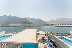 A rooftop pool area with a view of mountains and a body of water. - Sea Views 4BR + Assistant's Room Villa with Private Pool, Sharm - Al Dana Villa, Al Dana Island (Fujairah)