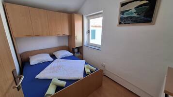 Une chambre à coucher avec un lit, une armoire en bois, une fenêtre donnant sur un beau paysage et un tableau accroché au mur.