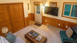A cozy living room with a wooden ceiling, a sofa, a coffee table, and a TV mounted on the wall. - Secluded Chalet near Ohiopyle and Seven Springs (Bear Rocks)