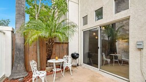 Une terrasse avec une clôture en bois, un palmier et un barbecue.
