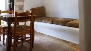 Un comedor con pared de piedra, una mesa de madera y un sofá con cojines.