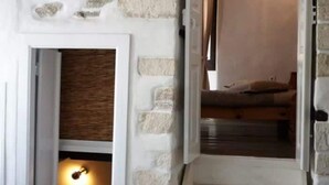 Una escalera con paredes de piedra y una puerta de madera que da a un dormitorio.