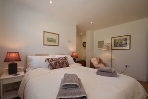 Une chambre à coucher bien aménagée, avec un grand lit, deux lampes de chevet, une table de chevet, une chaise et une lampe fixée au mur.