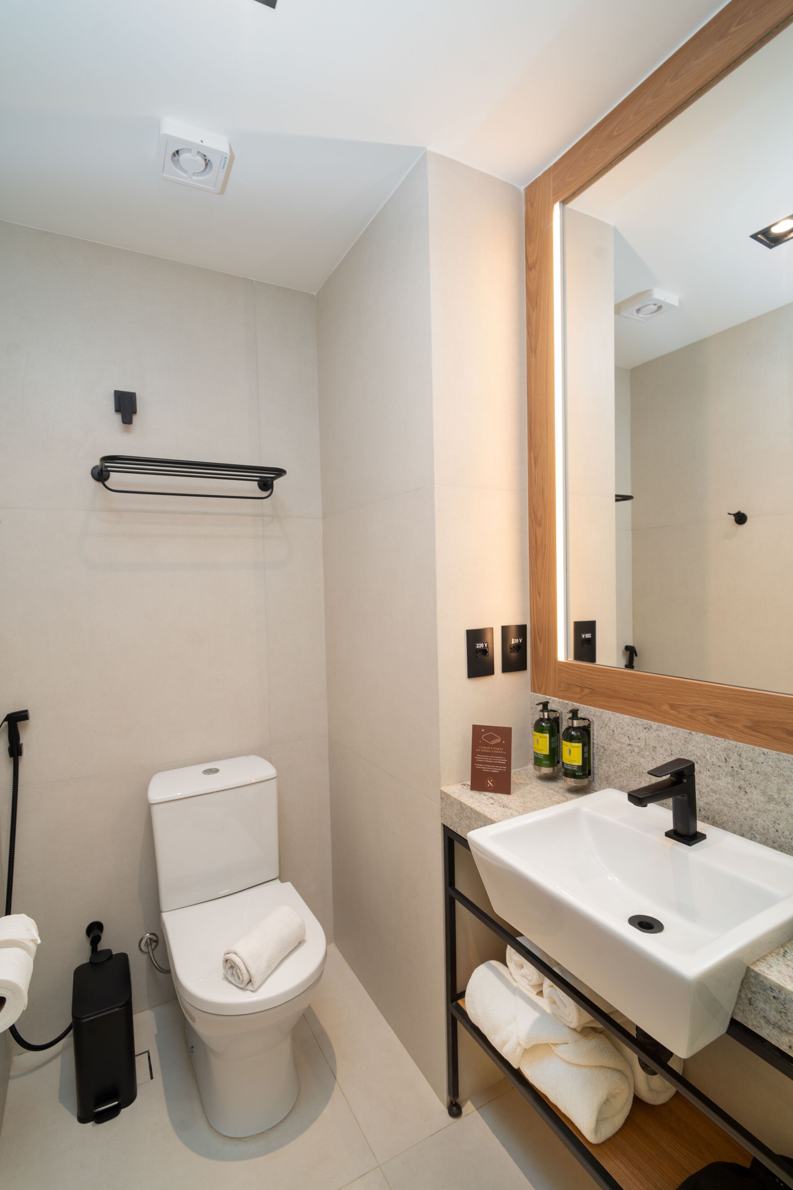 Un bagno moderno con un water bianco, un lavandino, uno specchio e un porta asciugamani.