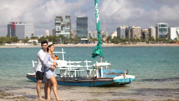 Una pareja parada cerca de un bote con el perfil urbano de una ciudad al fondo.