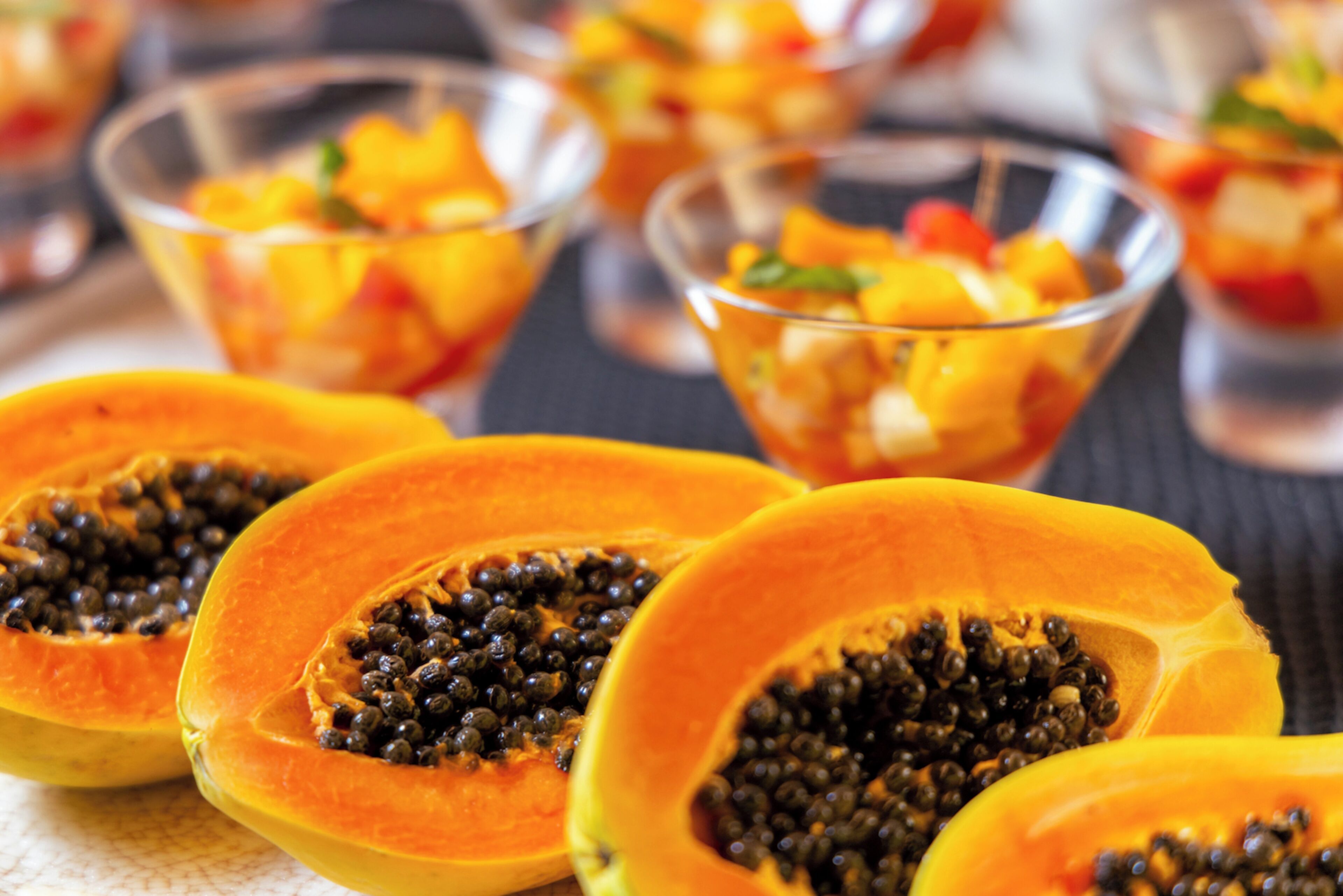 Primer plano de una ensalada de frutas con trozos de papaya y mango.
