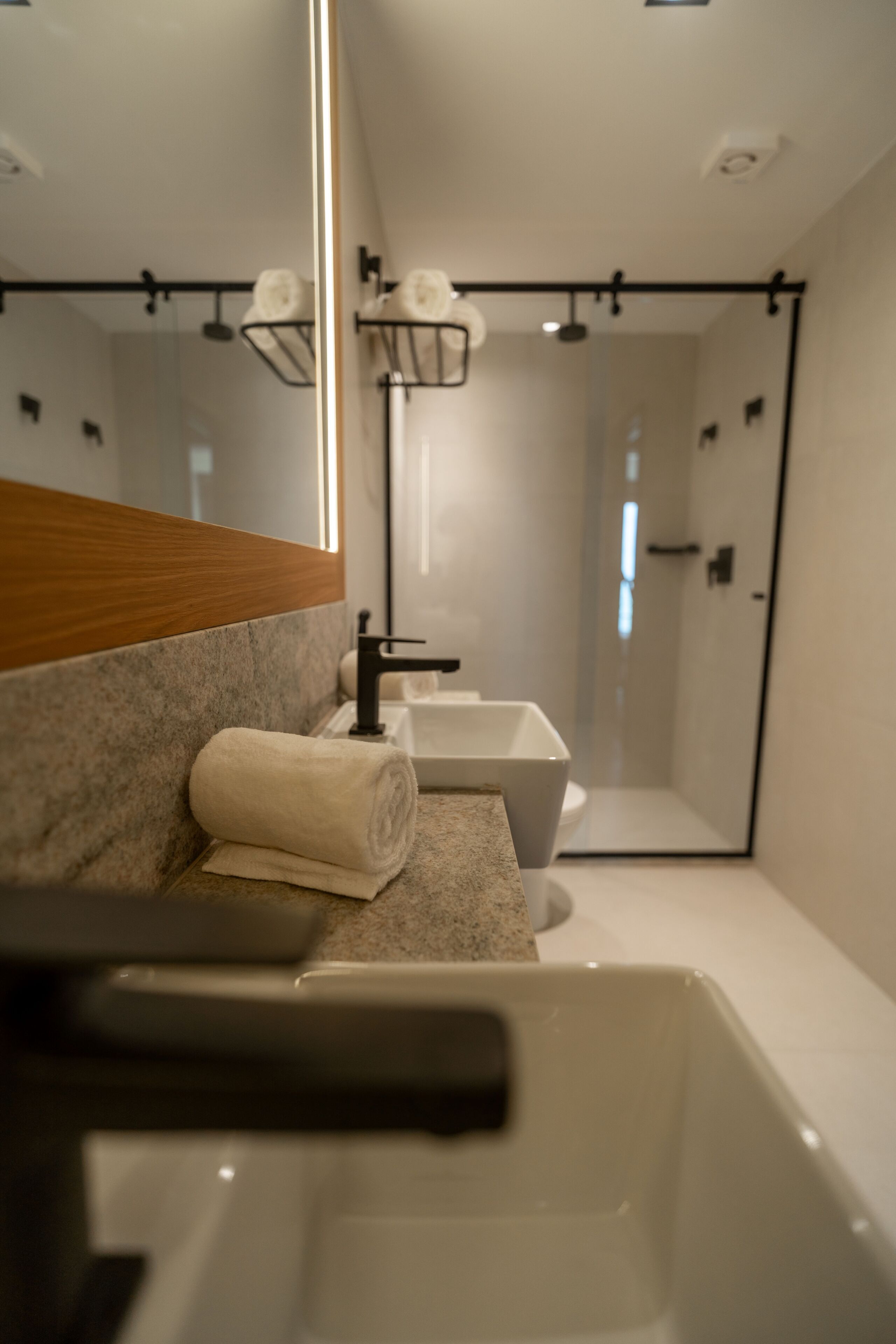 Un baño moderno con un espejo grande, dos lavamanos y una zona de ducha.