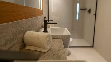 Un baño moderno con un espejo grande, dos lavamanos y una zona de ducha.