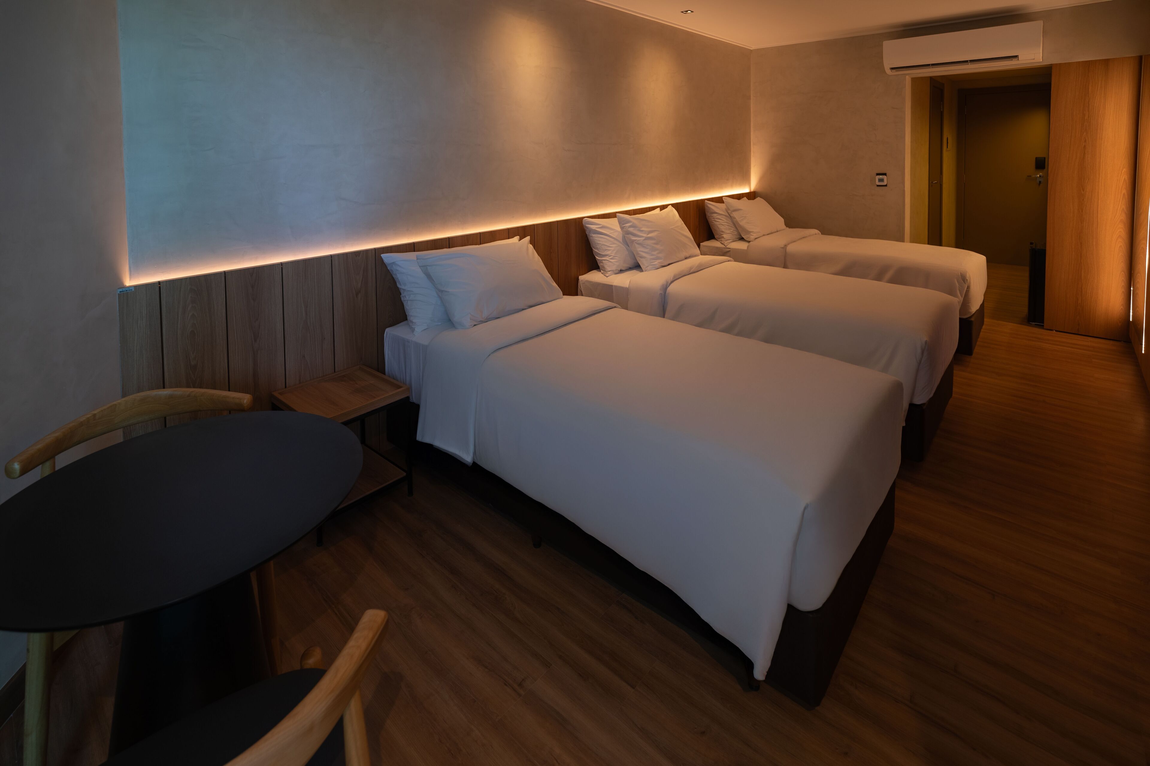 Ein Hotelzimmer mit zwei Einzelbetten, einem kleinen Tisch und einem Stuhl.
