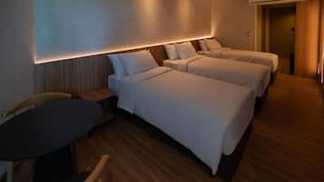 A hotel room with two single beds, a small table, and a chair.