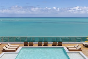 Zona de piscina con sillones y vista al océano.