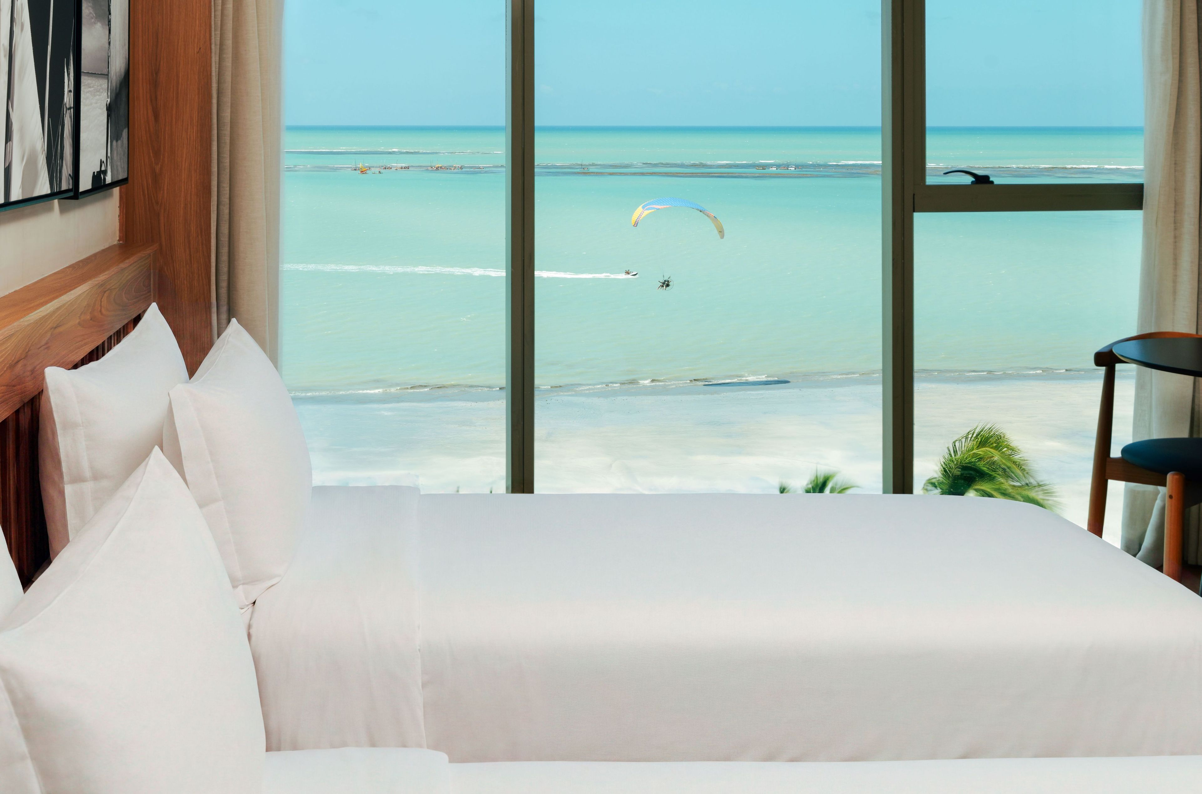 Habitación de hotel con un amplio ventanal que ofrece vistas a la playa y al océano.