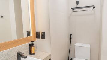 A bathroom with a sink, mirror, toilet, and shower.