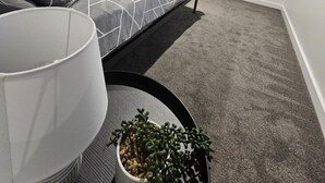 Une chambre à coucher moderne avec un lit, une table de chevet dotée d’une lampe et une plante en pot.