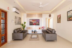 A modern living room with two grey sofas, a coffee table, and a TV mounted on the wall. - Euphoria Penthouse (Hyderabad)