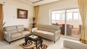 Ein Wohnzimmer mit zwei beigefarbenen Sofas, einem Couchtisch und einer großen Schiebetür zu einem Außenbereich mit Möbeln.