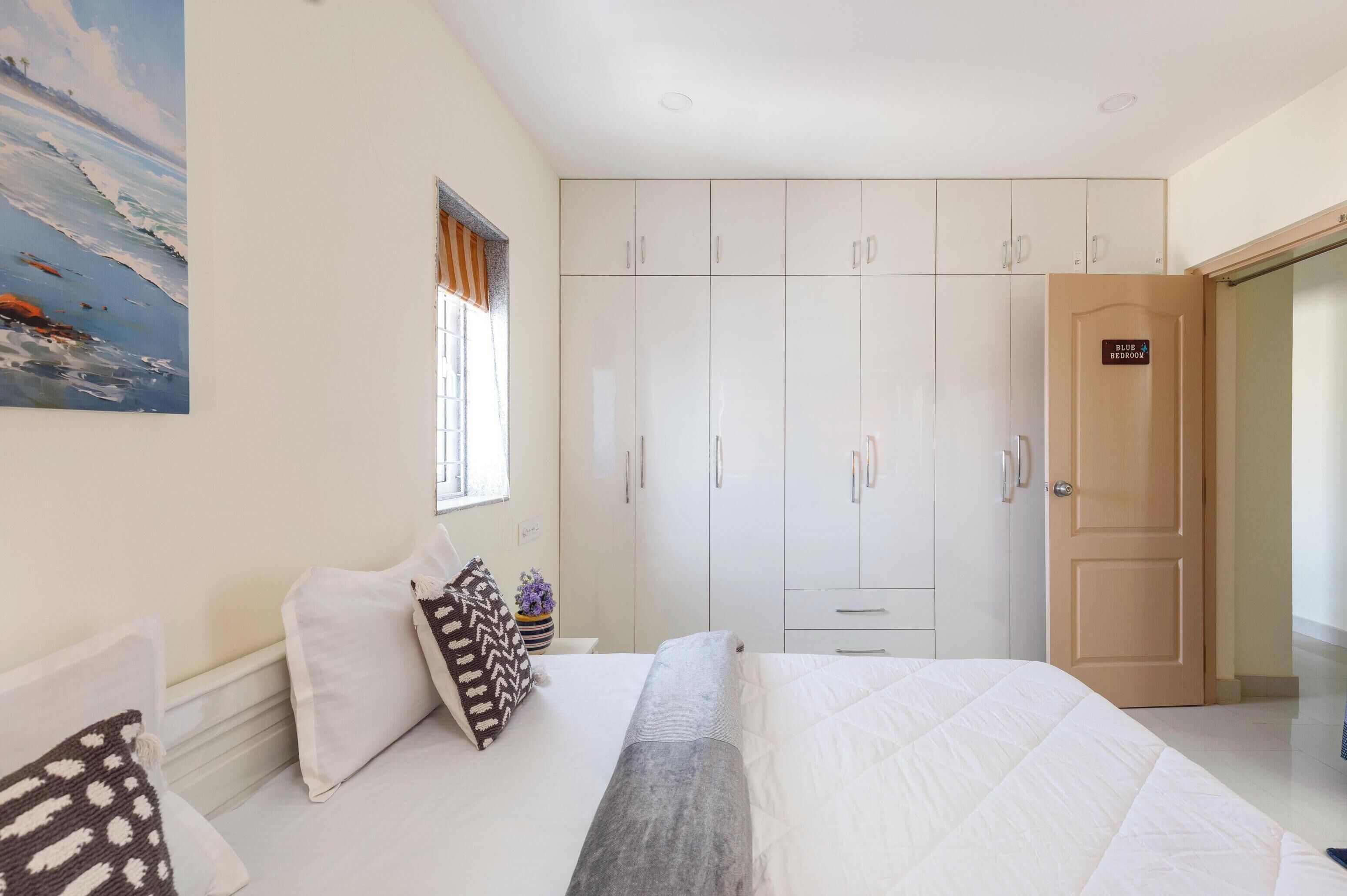A bedroom with a bed, pillows, a wardrobe, and a door labeled "Blue Bedroom".