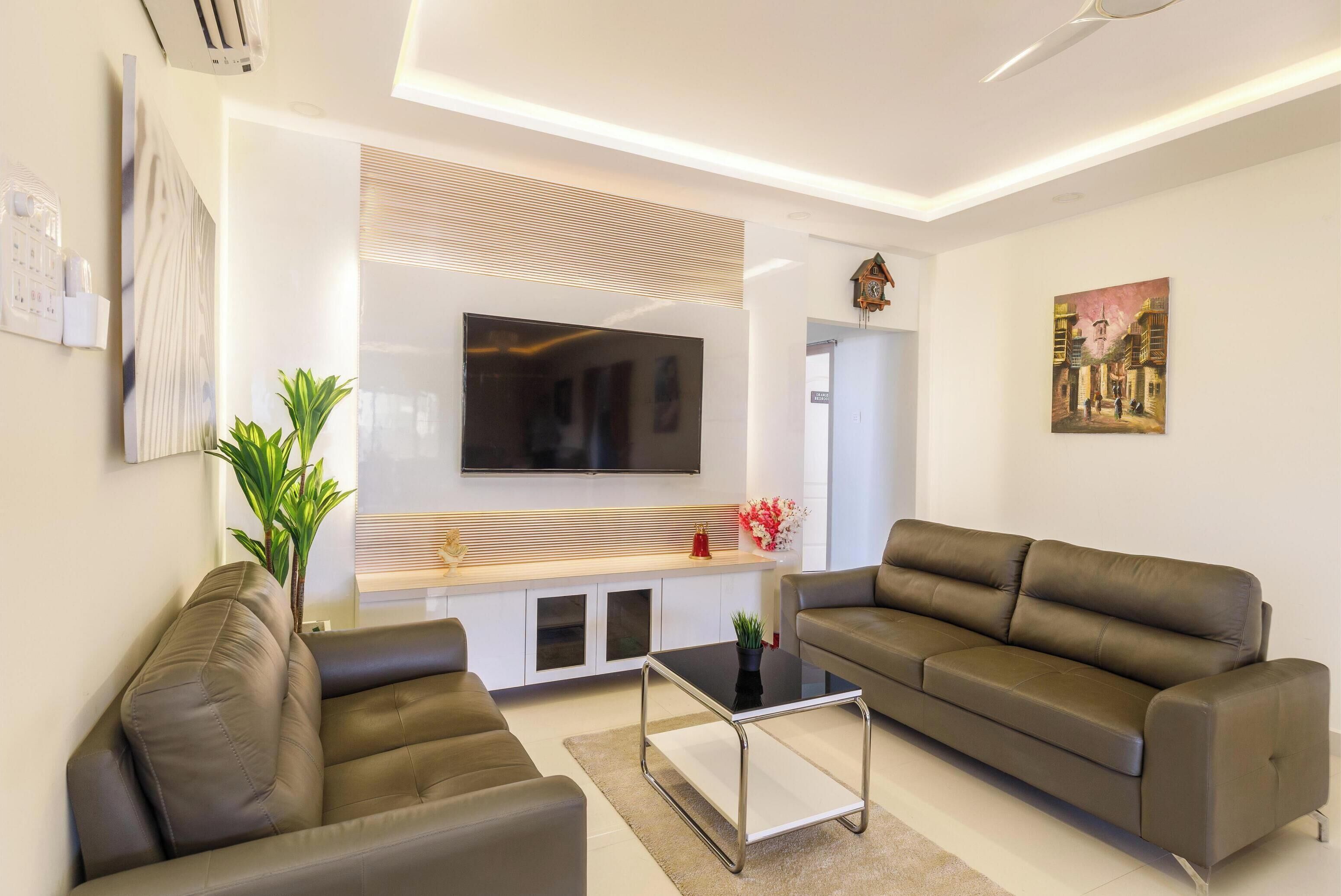 A modern living room with two sofas, a coffee table, a flat-screen TV, and a painting on the wall.
