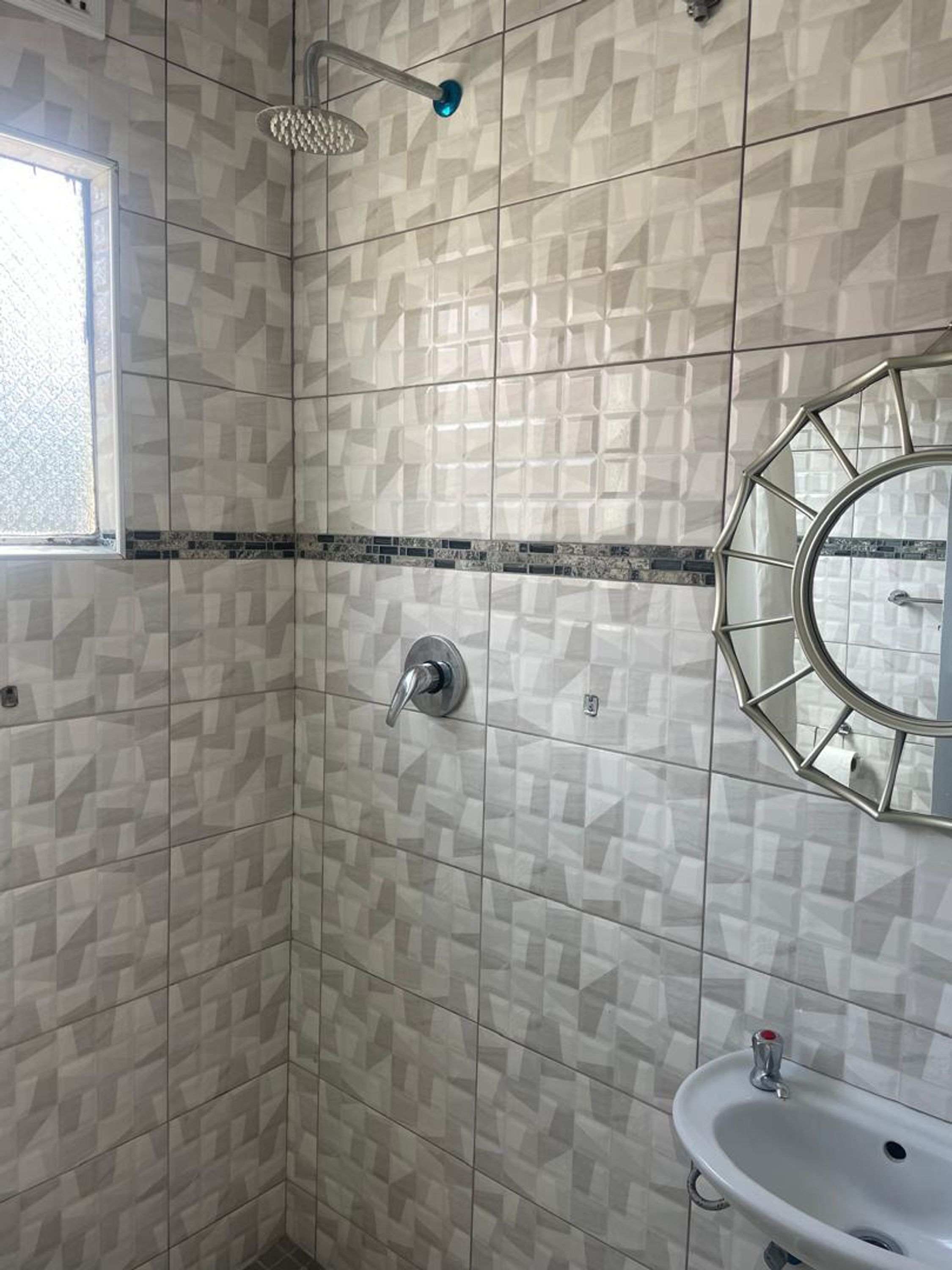 A bathroom with a shower, a sink, and a mirror.