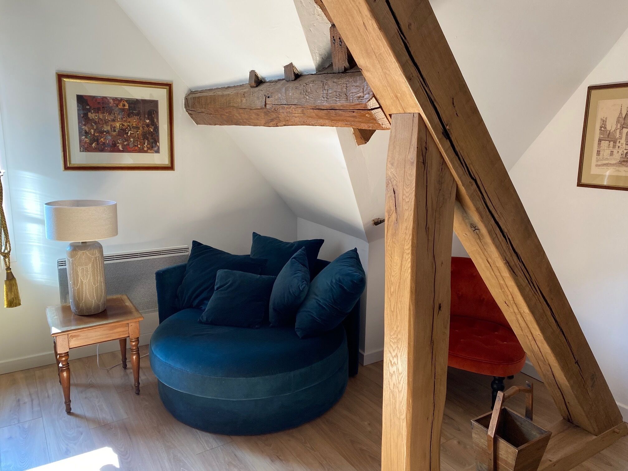 Ein gemütliches Zimmer mit einem blauen Sofa, einem Holztisch mit einer Lampe und einem roten Sessel.