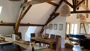 Una cucina rustica con travi in legno, un tavolo da pranzo, sedie e un'ampia finestra.