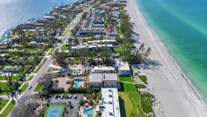 An aerial view of a coastal residential area with houses, a beach, and a marina. - Gulf-Front Grandeur in Longboat Key – Luxurious & Spacious Condo #102 by RVA (Longboat Key)