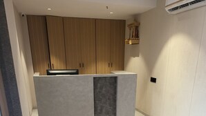 A modern kitchen with a central island, a sofa, and a tiled floor. - Hotel Shiv Kartik (Surat)