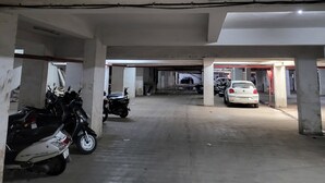 An underground parking garage with concrete pillars and a flat ceiling. - Hotel Shiv Kartik (Surat)