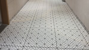 A long, narrow hallway with patterned floor tiles and recessed lighting along the walls. - Hotel Shiv Kartik (Surat)